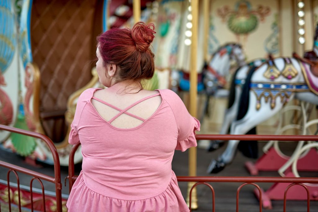 Plus Size woman next to carousel - What to Wear to an Amusement Park Plus Size Guide
