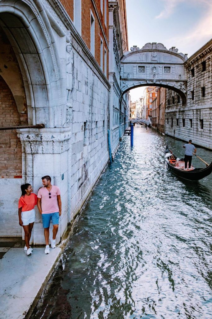 Two people in Venice in June next to gondola and rialto bridge
