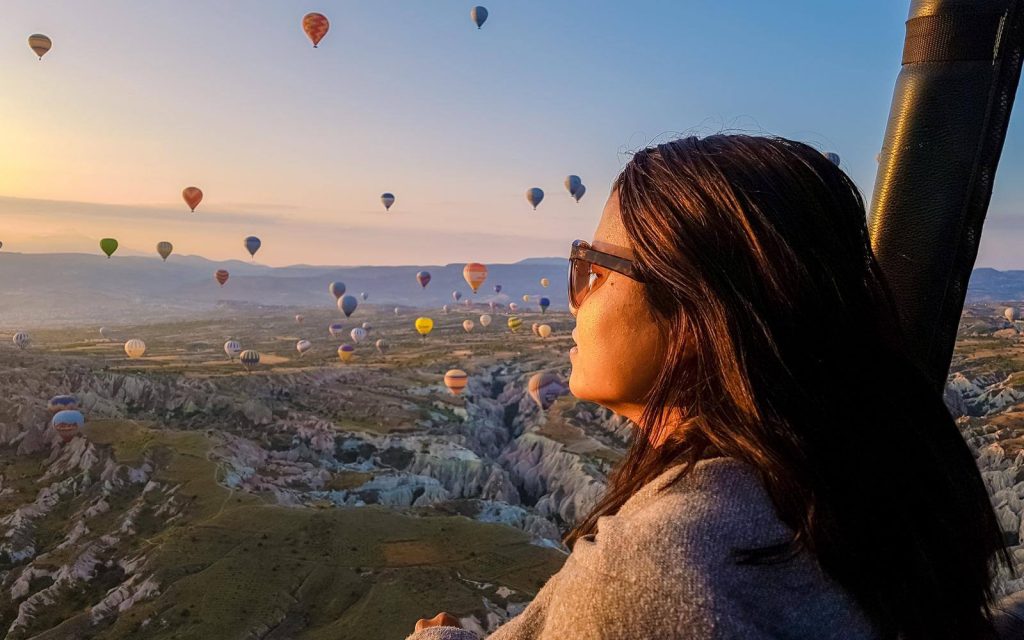 Woman in hot air balloon looking at other balloon