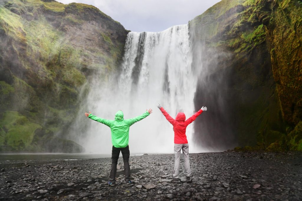 Couple in front of Skogafoss Waterfall in Iceland wearing waterproof jackets 