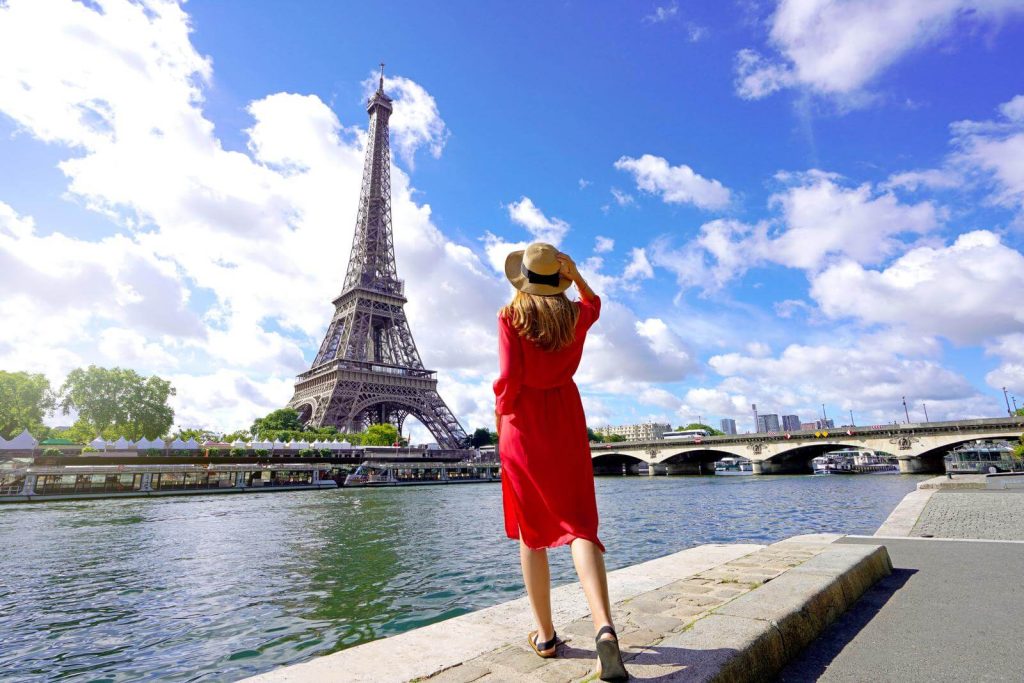 Woman in red dress in front of river and Eiffel tower