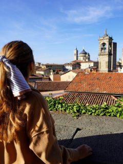 Woman in jacket, back turned to camera overlooking the Bergamo Italy skyline in October