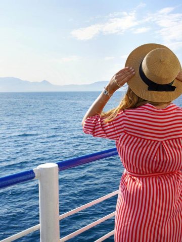 Woman holding straw hat on cruise ship
