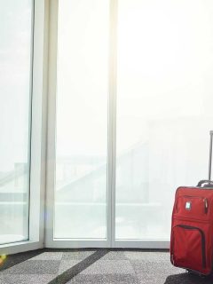 MAn standing next to red suitcase at airport