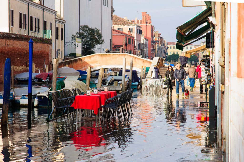 Street in VEnice flooded with table and people outside in Winter