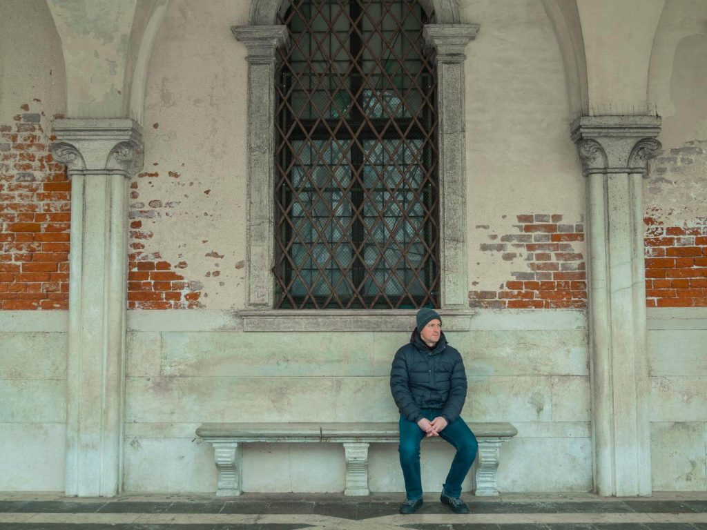 Man sitting wearing Winter outfit in VEnice in December