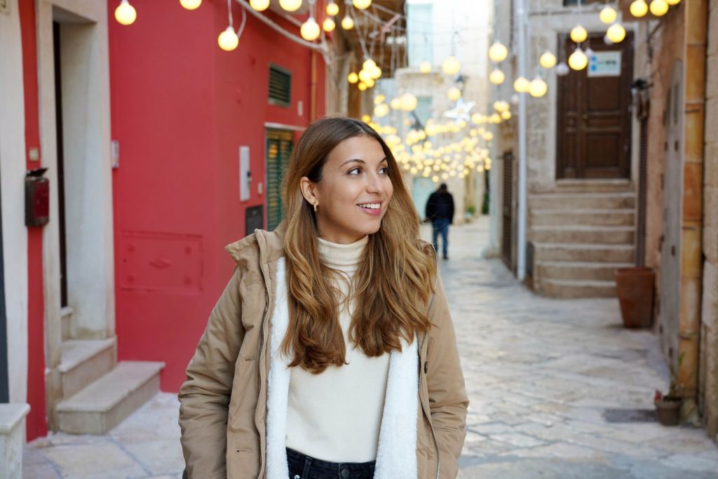 Woman in Winter outfit in European street with twinkling lights 