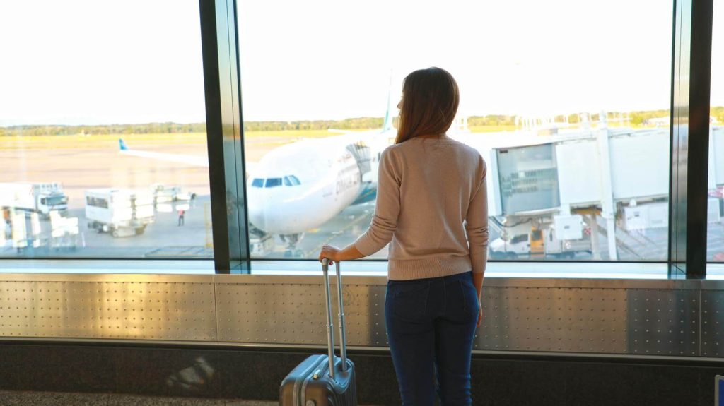 Woman looking at airplane from airport in Winter