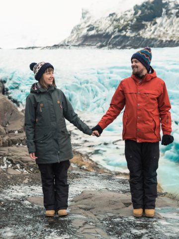 Couple holding hands while wearing winter clothes in Iceland in January next to Glacier