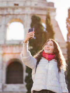 Woman in Rome in December standing in front of the Colosseum taking a selfie