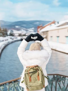 Woman with her back to camera making heart sign overlooking the Otaru canal Hokkaido in Winter