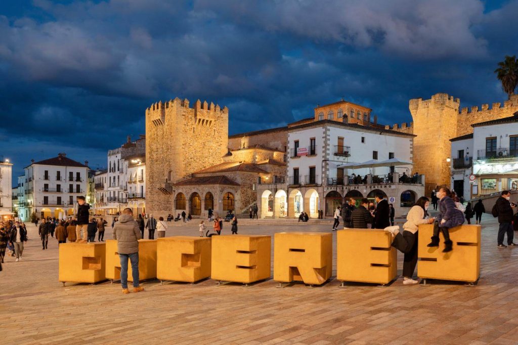 View of Caceres Spain old town at night in March with people in coats in the foreground
