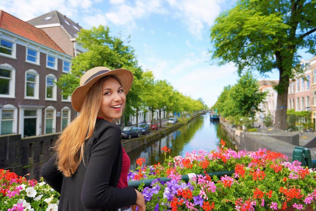 Woman in cardigan next to canal covered in spring flowers