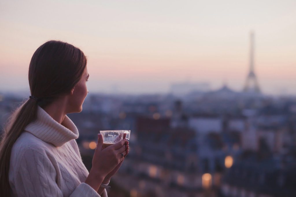 Woman in France in February holding a hot drink overlooking the Eiffel Tower