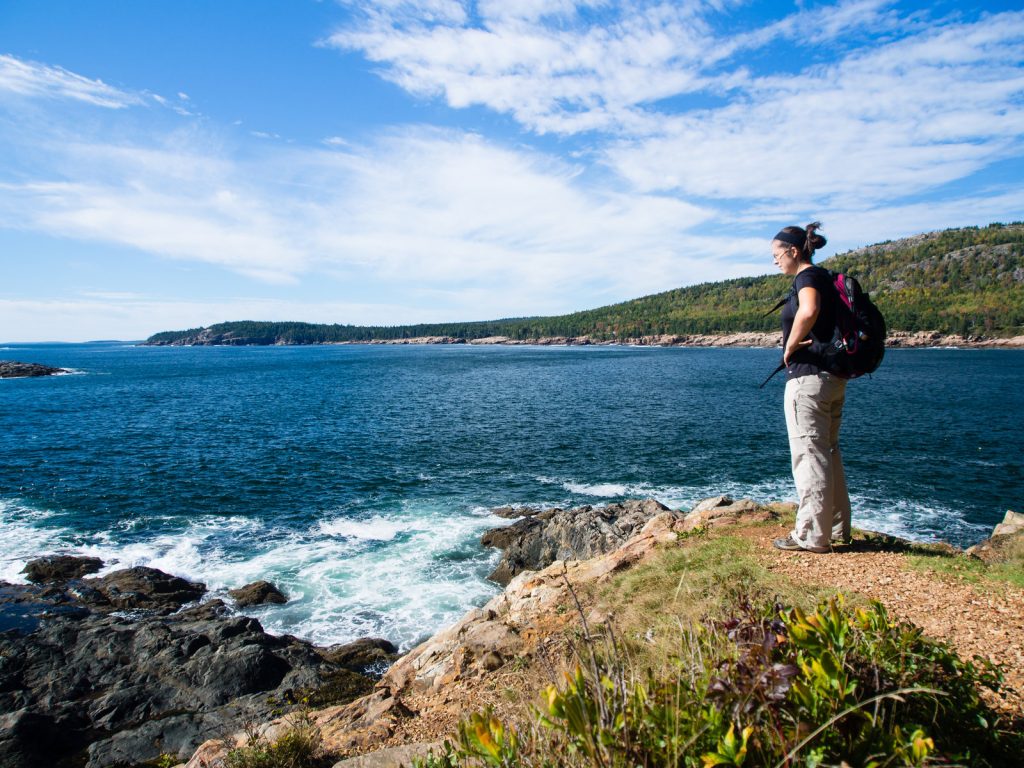 Woman stood on cliff next to sea in Acadia National Park in Summer