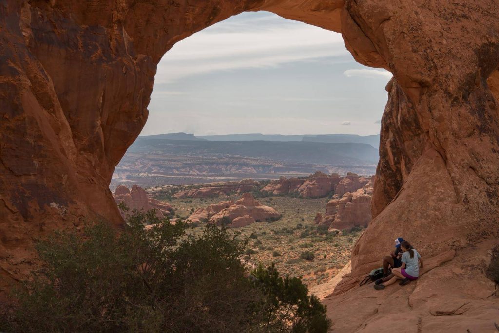 Man and woman sitting in front of Windows arches in Arches national park
