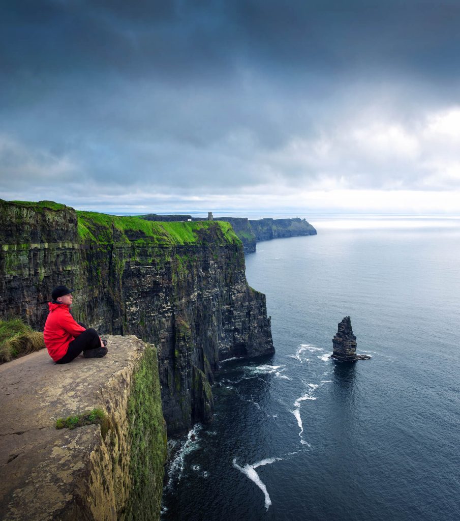 MAn sat on rock at Cliffs of Moher