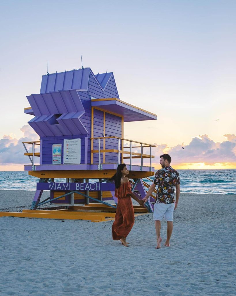 Couple stood in front of purple lifeguard hut on Miami Beach