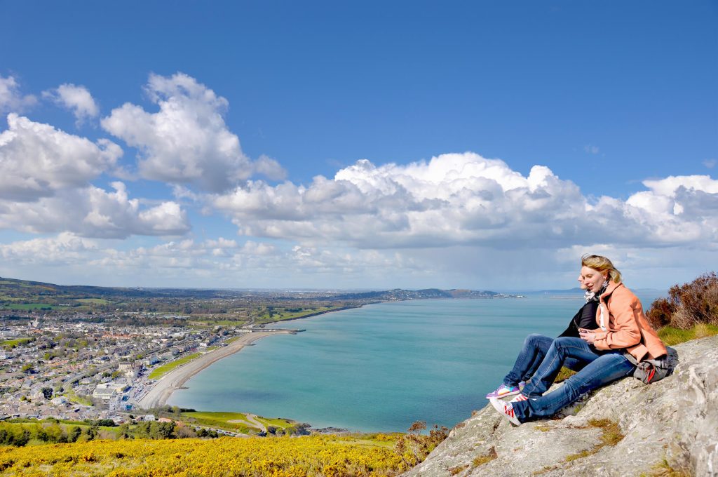 Woman sat on rock above the coastline in Ireland