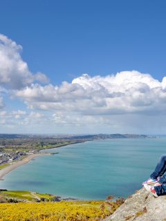 Woman sat on rock above the coastline in Ireland