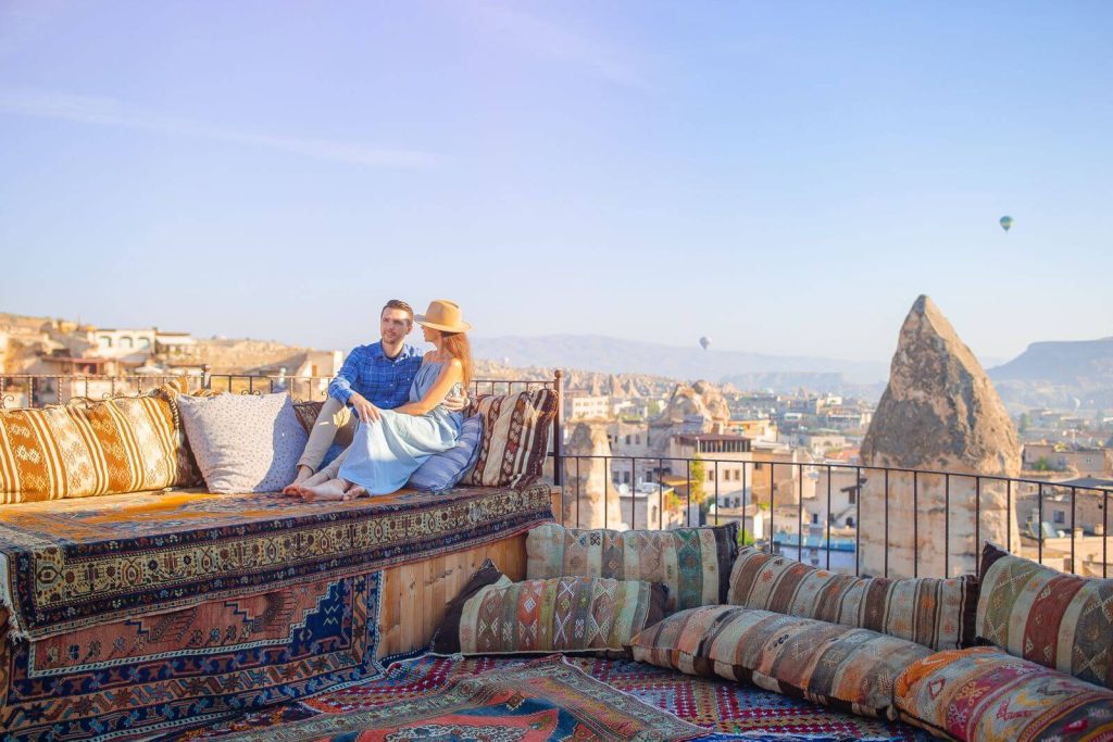 Couple sat on rooftop looking at balloons in Cappadocia
