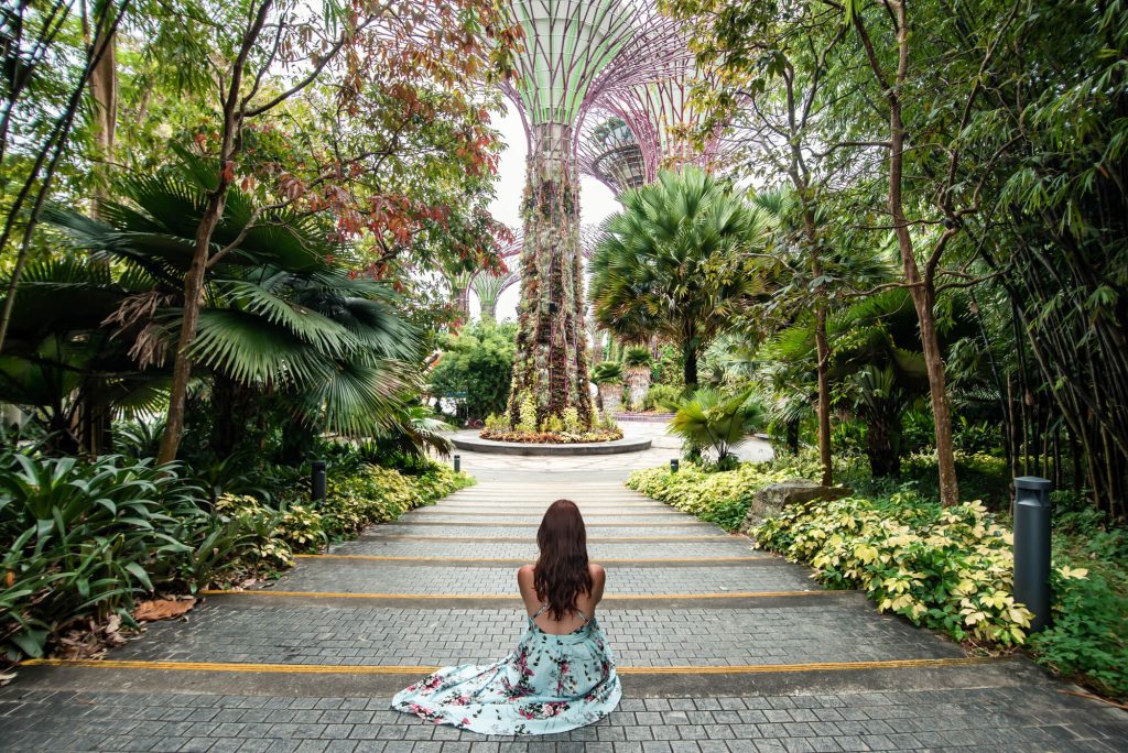 Woman sat on the floor in long dress at the entrance to the Gardens of the Bay in Singapore